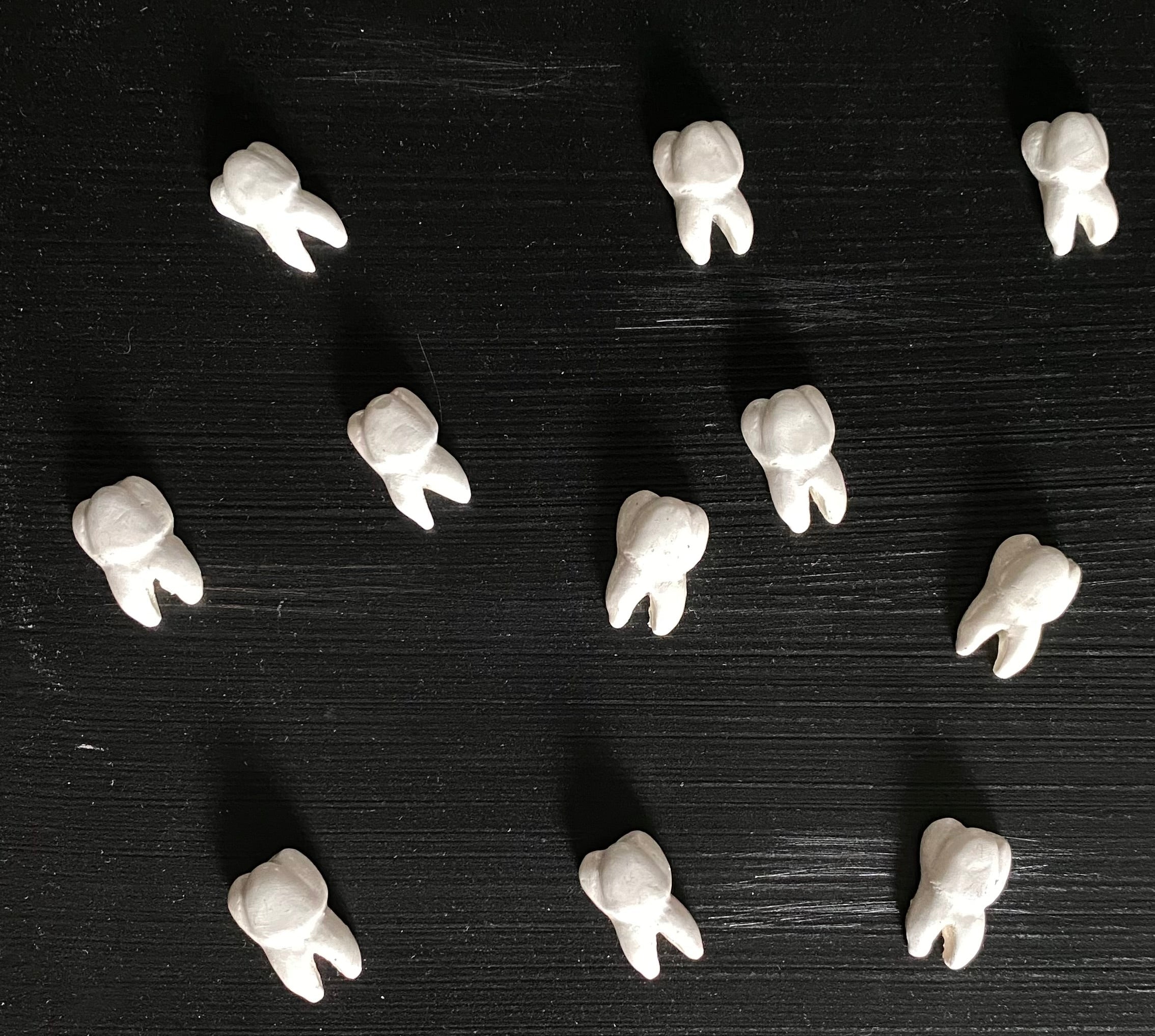 Tooth-shaped objects on a black textured surface